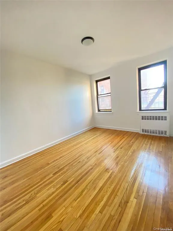Empty room featuring light wood-type flooring and radiator heating unit Empty room featuring light wood-type flooring and radiator heating unit