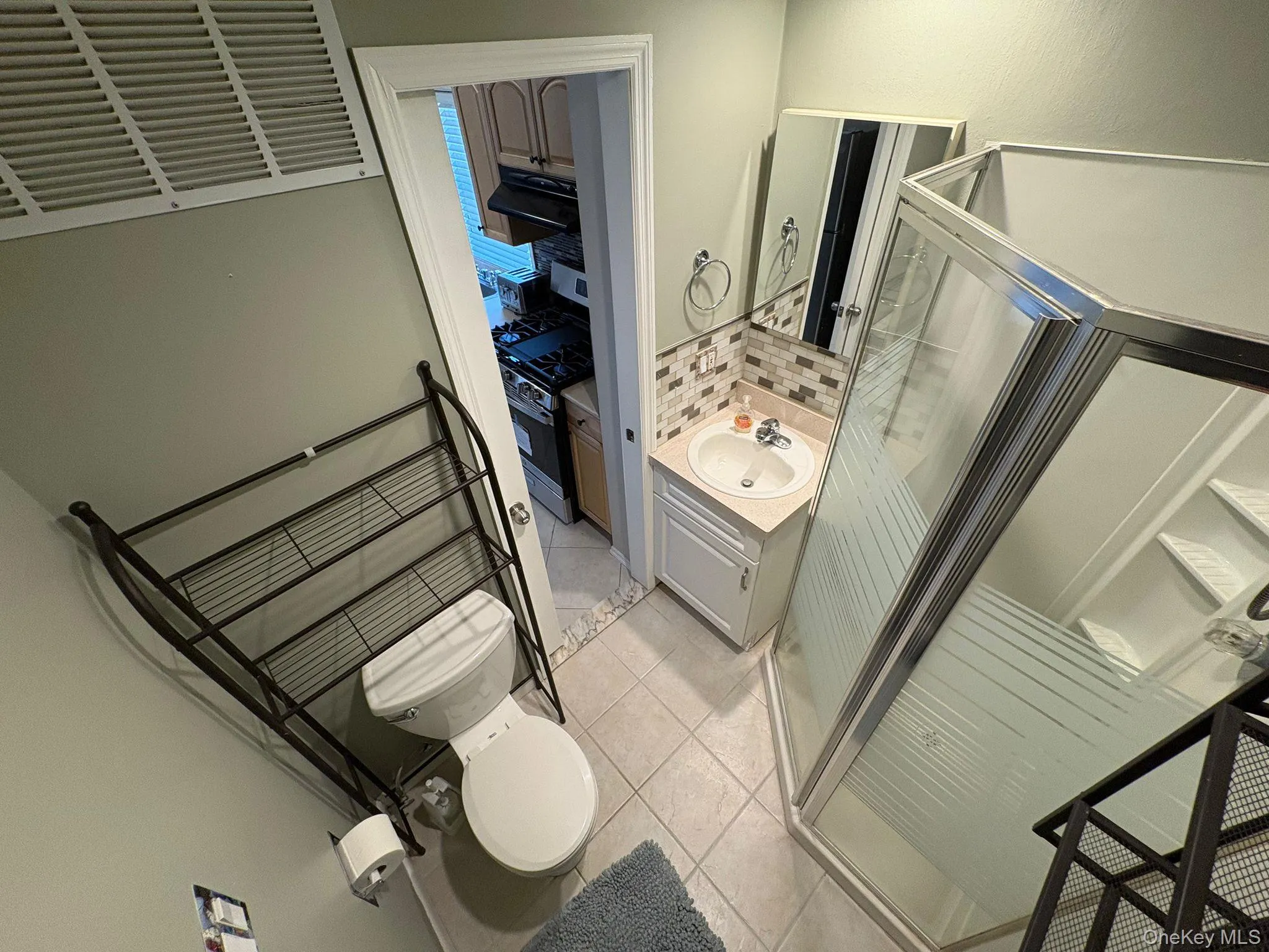 Full bathroom featuring vanity, light tile patterned floors, a shower stall, and decorative backsplash Full bathroom featuring vanity, light tile patterned floors, a shower stall, and decorative backsplash