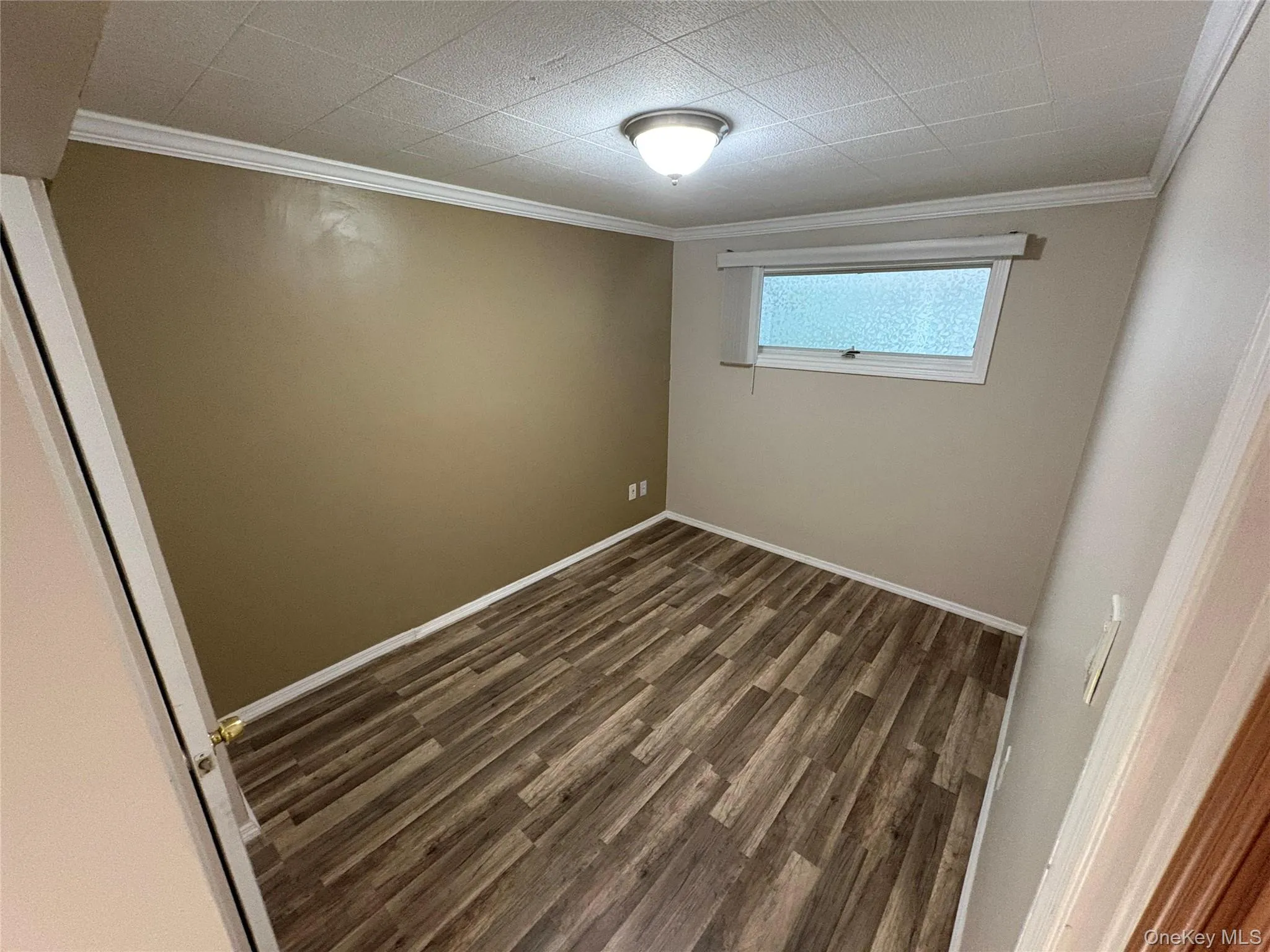 Empty room with ornamental molding and dark wood-style flooring Empty room with ornamental molding and dark wood-style flooring