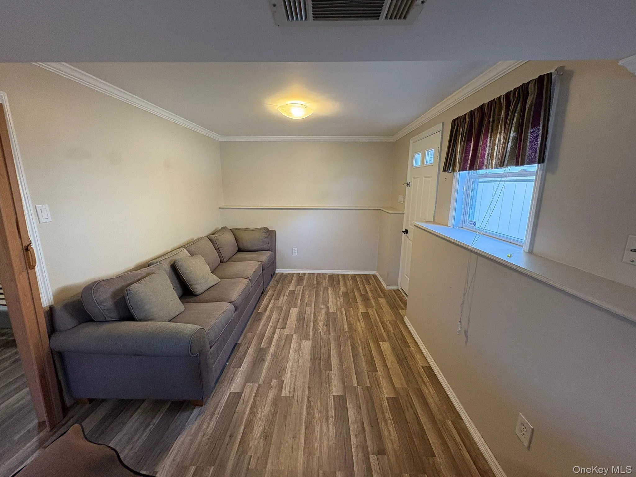 Living area with crown molding and wood finished floors Living area with crown molding and wood finished floors