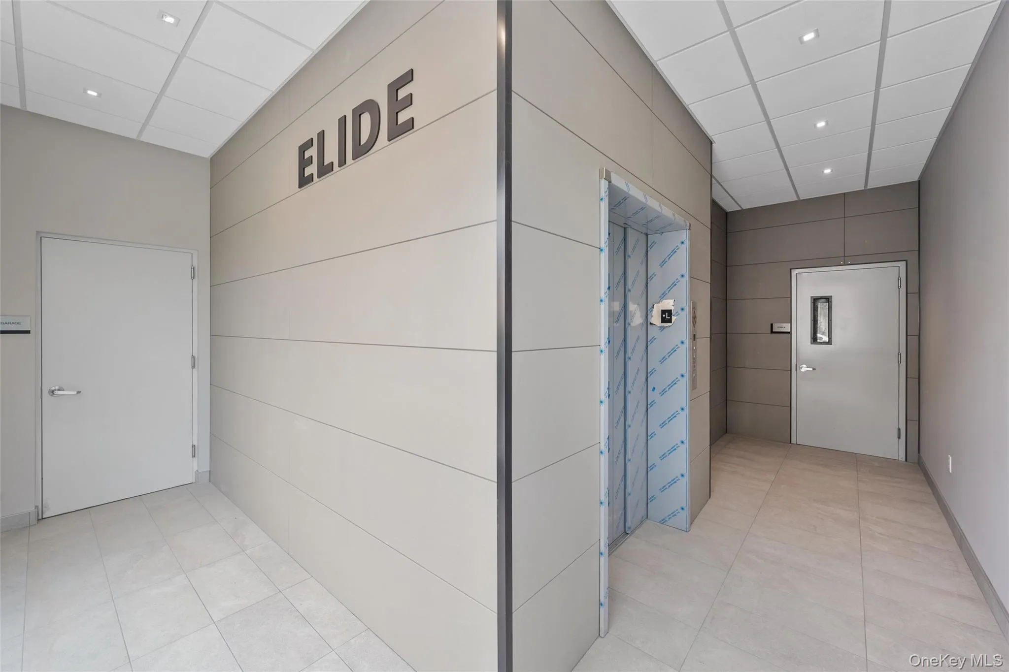 Hall featuring a drop ceiling, light tile patterned floors, and recessed lighting Hall featuring a drop ceiling, light tile patterned floors, and recessed lighting