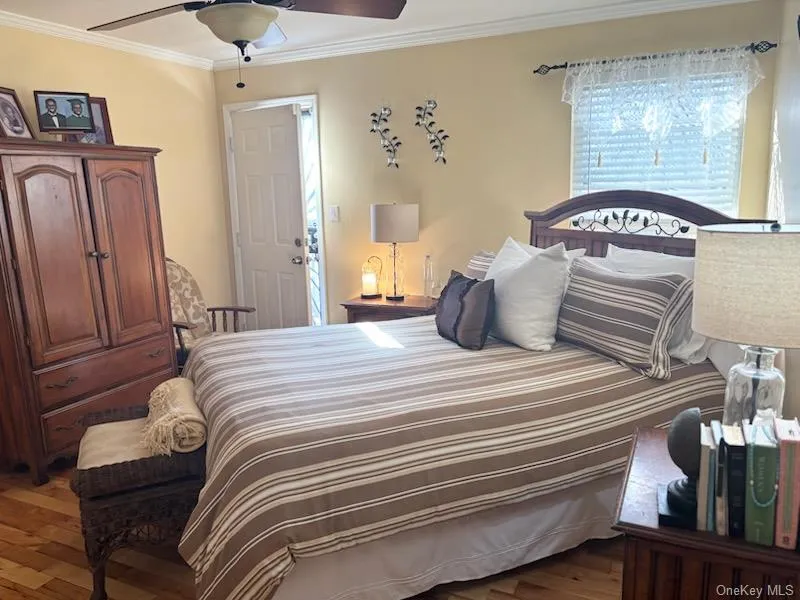 Bedroom with ornamental molding, dark wood-style floors, and ceiling fan Bedroom with ornamental molding, dark wood-style floors, and ceiling fan