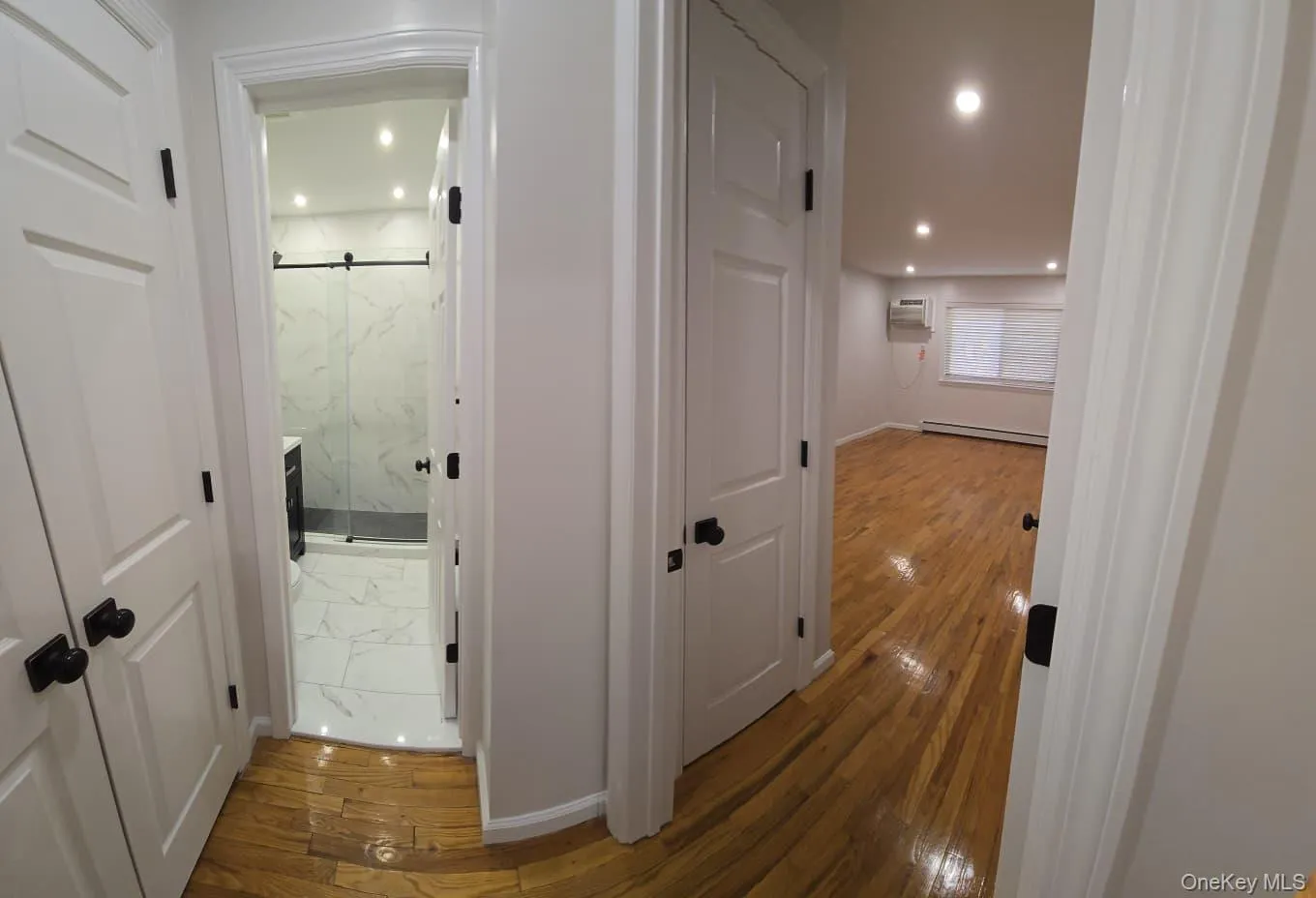 Hallway with hardwood / wood-style floors, recessed lighting, and baseboard heating Hallway with hardwood / wood-style floors, recessed lighting, and baseboard heating