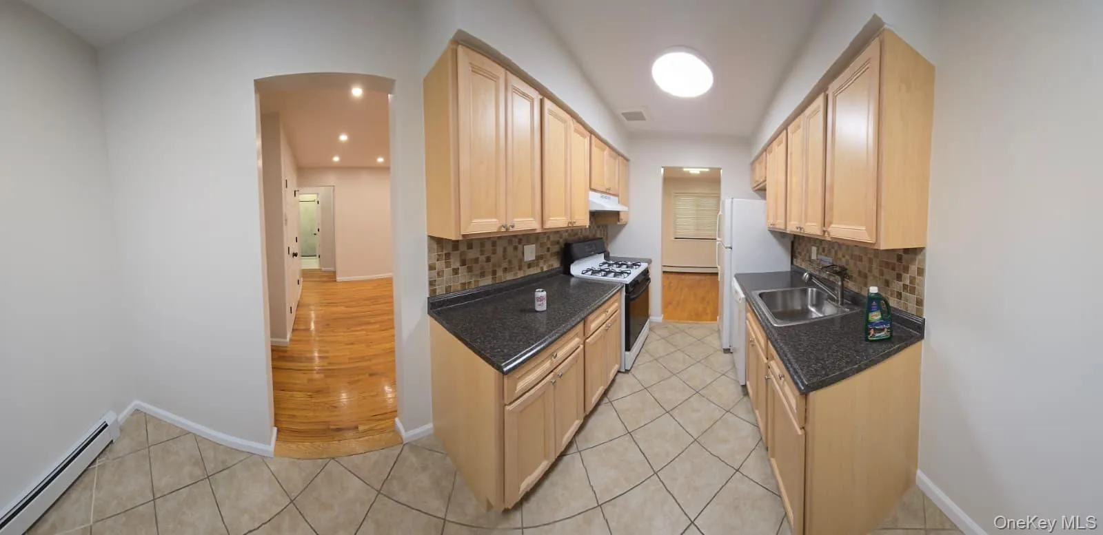 Kitchen with baseboard heating, white appliances, light tile patterned flooring, arched walkways, and recessed lighting Kitchen with baseboard heating, white appliances, light tile patterned flooring, arched walkways, and recessed lighting