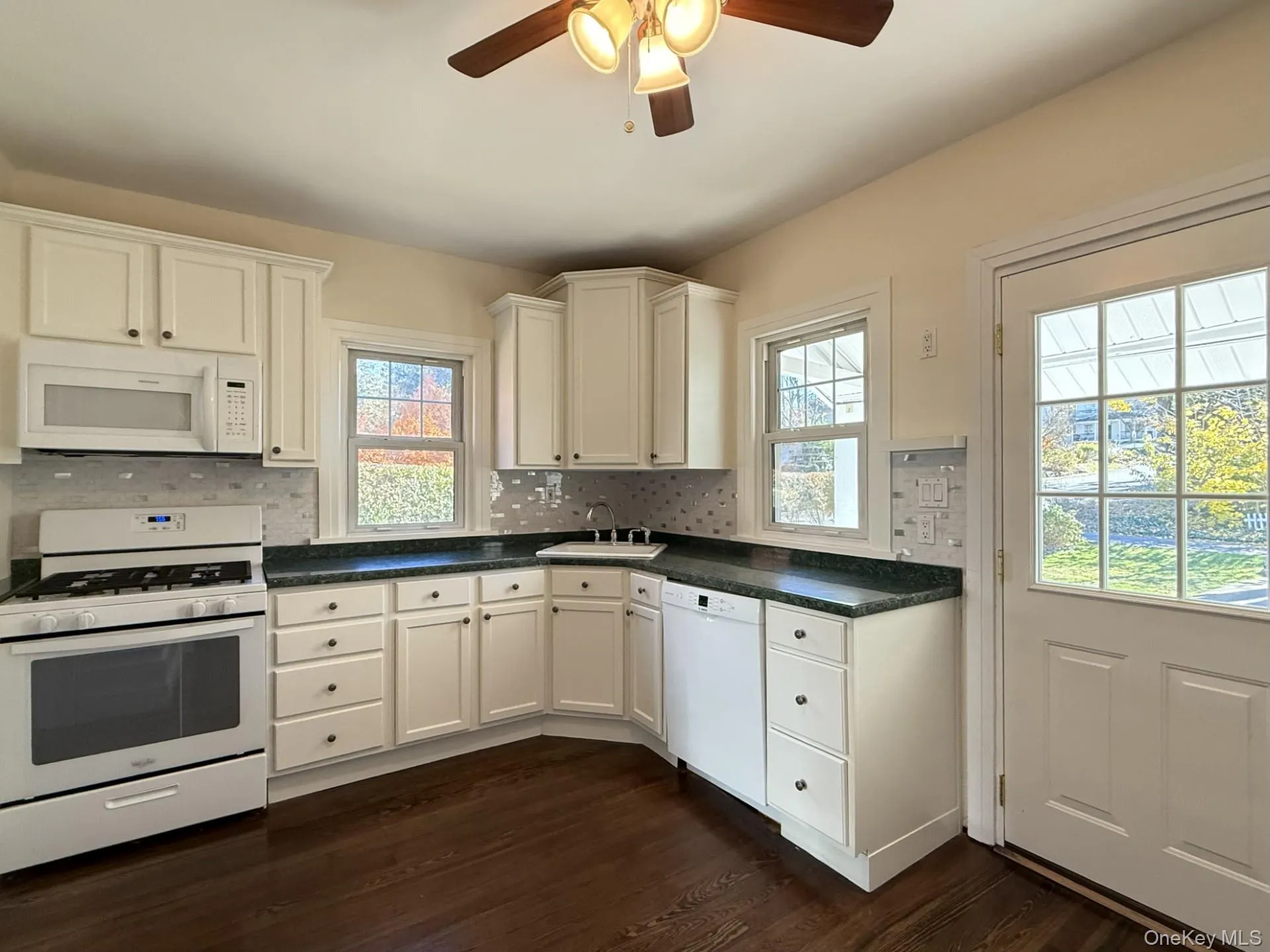 Kitchen featuring white appliances, dark countertops, white cabinets, and ceiling fan Kitchen featuring white appliances, dark countertops, white cabinets, and ceiling fan