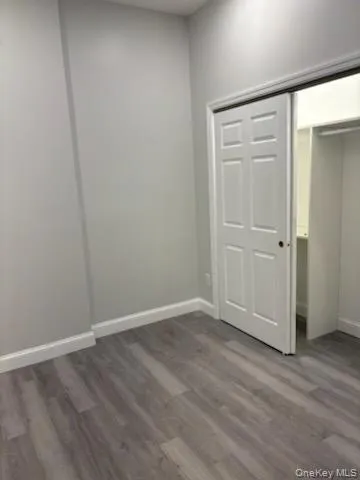 Unfurnished bedroom with dark wood-style floors and a closet Unfurnished bedroom with dark wood-style floors and a closet