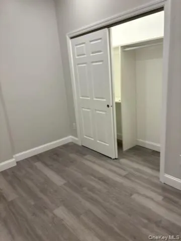 Unfurnished bedroom with dark wood finished floors and a closet Unfurnished bedroom with dark wood finished floors and a closet