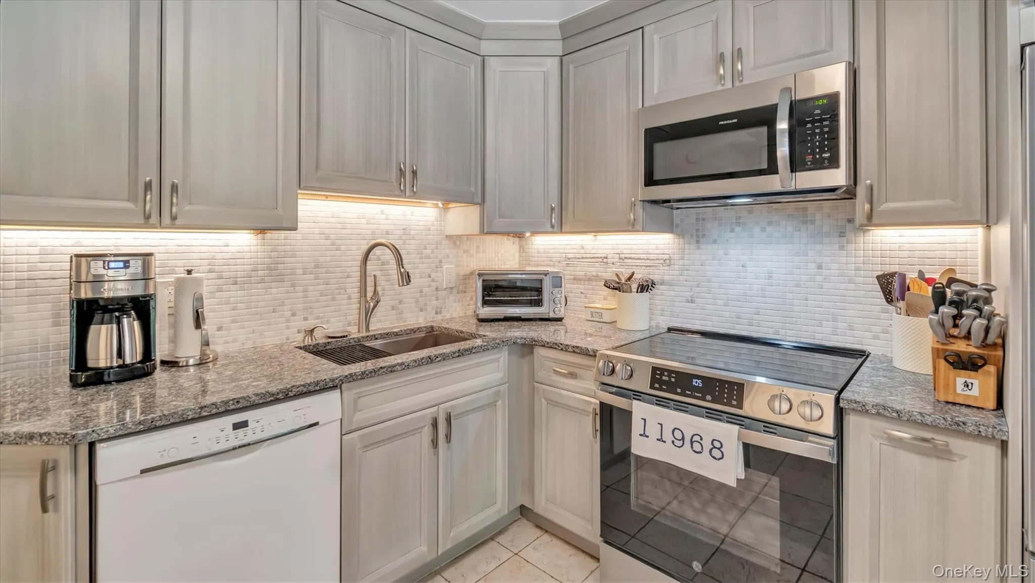 Kitchen with stainless steel appliances, backsplash, light stone counters, and light tile patterned floors Kitchen with stainless steel appliances, backsplash, light stone counters, and light tile patterned floors