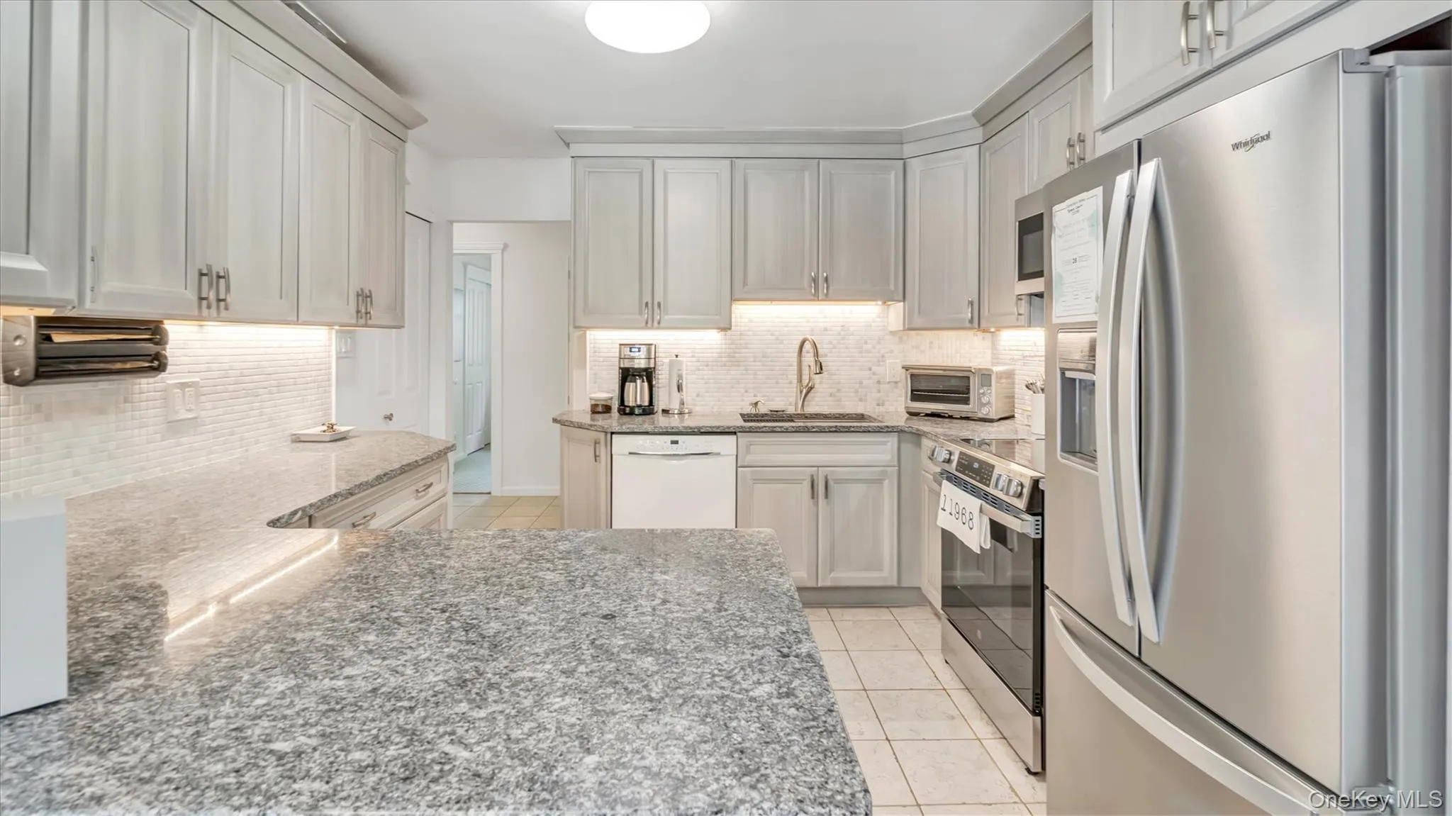 Kitchen with stainless steel appliances, light tile patterned flooring, light stone countertops, and tasteful backsplash Kitchen with stainless steel appliances, light tile patterned flooring, light stone countertops, and tasteful backsplash