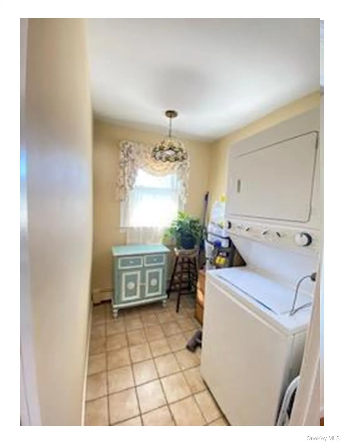 Laundry area with estacked washer and dryer and light tile patterned floors Laundry area with estacked washer and dryer and light tile patterned floors
