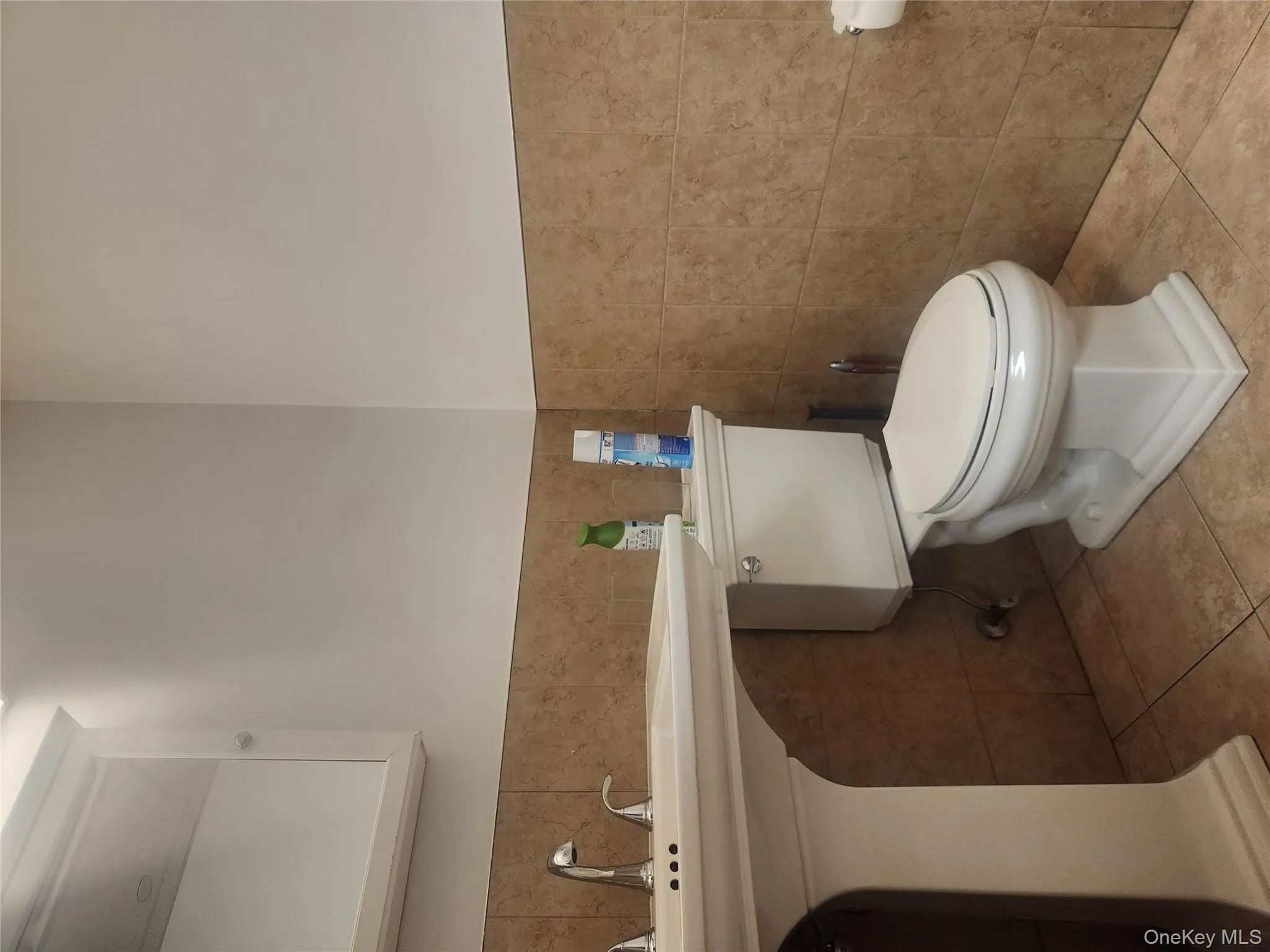Half bathroom featuring tile walls, tile patterned flooring, and a wainscoted wall Half bathroom featuring tile walls, tile patterned flooring, and a wainscoted wall
