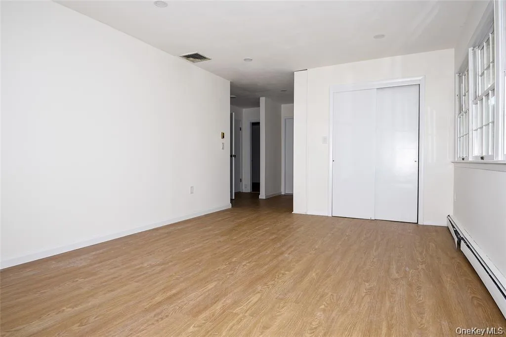 Unfurnished bedroom with a baseboard heating unit, light wood-style floors, and a closet Unfurnished bedroom with a baseboard heating unit, light wood-style floors, and a closet