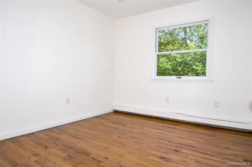 Empty room with a baseboard heating unit and wood finished floors Empty room with a baseboard heating unit and wood finished floors