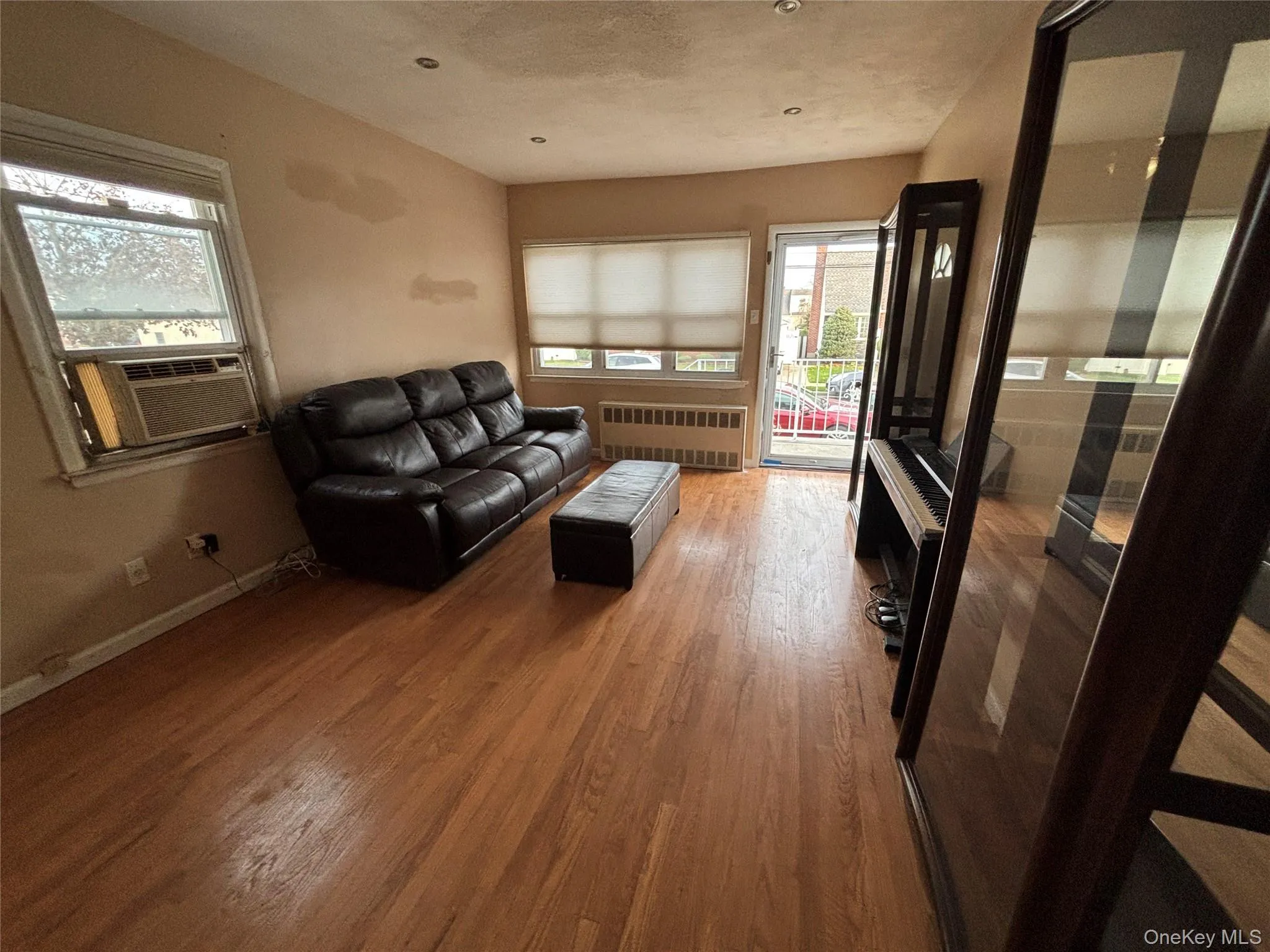 Living room featuring light wood-type flooring, radiator heating unit, and cooling unit Living room featuring light wood-type flooring, radiator heating unit, and cooling unit
