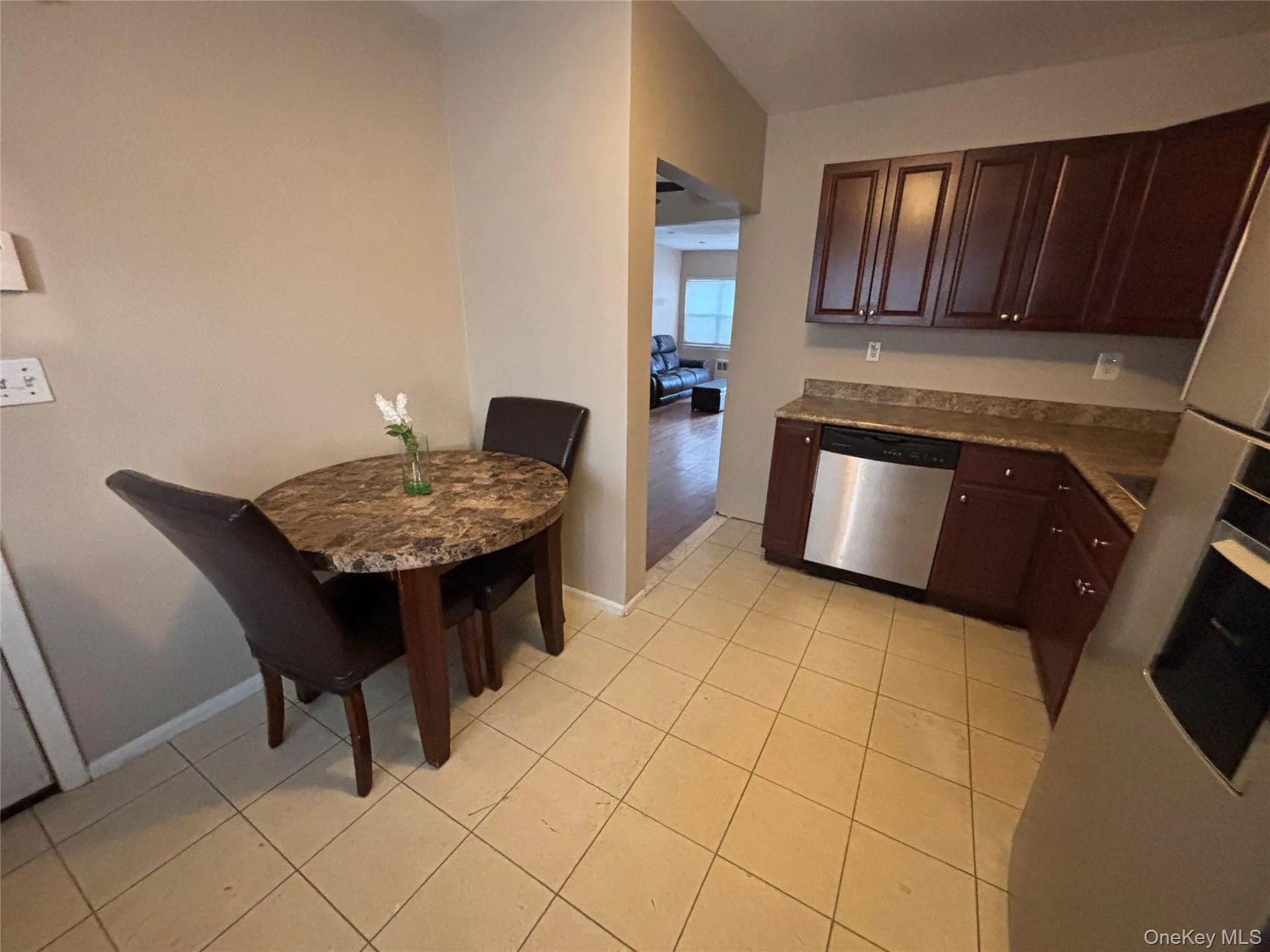 Kitchen featuring dishwasher, dark brown cabinetry, oven, and light tile patterned floors Kitchen featuring dishwasher, dark brown cabinetry, oven, and light tile patterned floors