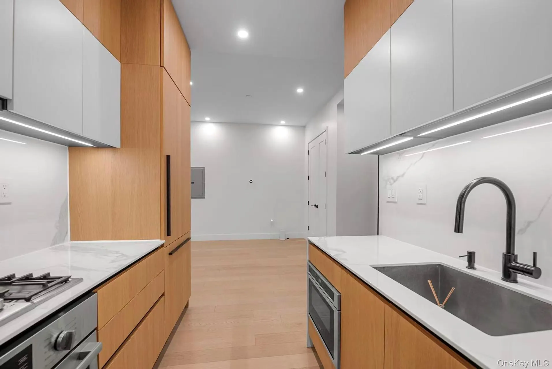 Kitchen featuring modern cabinets, recessed lighting, appliances with stainless steel finishes, light stone counters, and light wood-style floors Kitchen featuring modern cabinets, recessed lighting, appliances with stainless steel finishes, light stone counters, and light wood-style floors