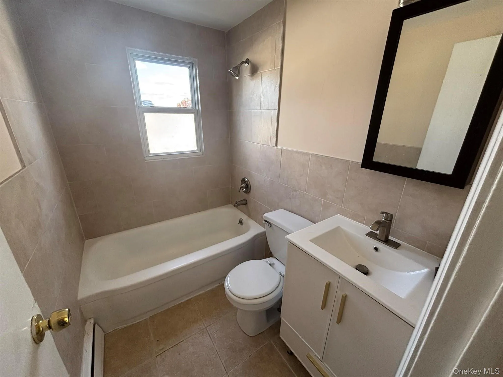 Full bath featuring vanity, tile walls, light tile patterned floors, and shower / tub combination Full bath featuring vanity, tile walls, light tile patterned floors, and shower / tub combination
