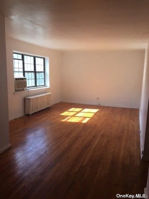 Empty room featuring wood finished floors and radiator heating unit Empty room featuring wood finished floors and radiator heating unit