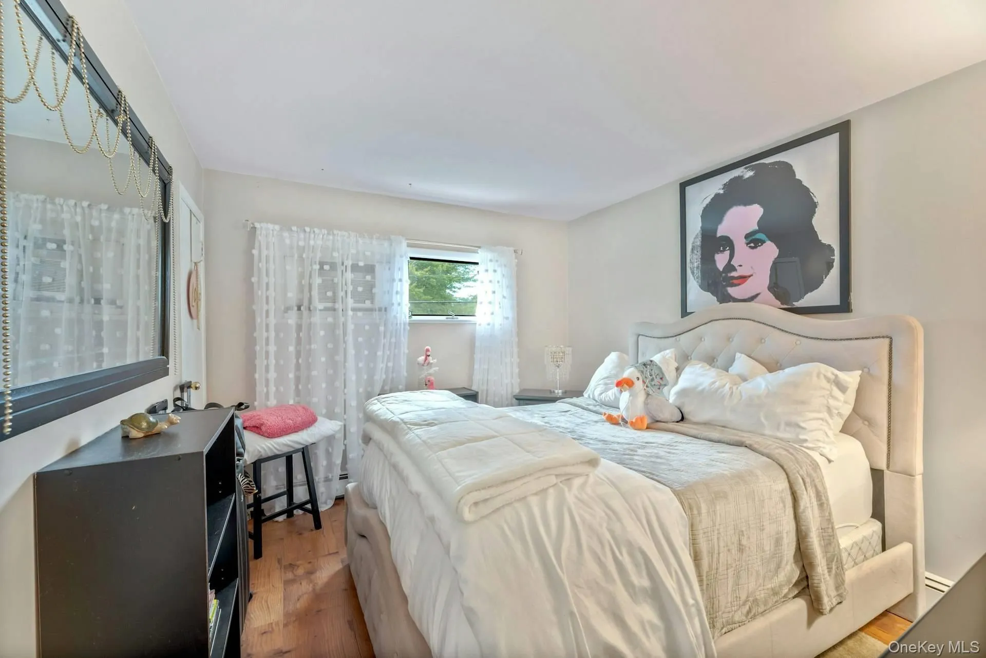Bedroom featuring wood finished floors and a baseboard radiator Bedroom featuring wood finished floors and a baseboard radiator