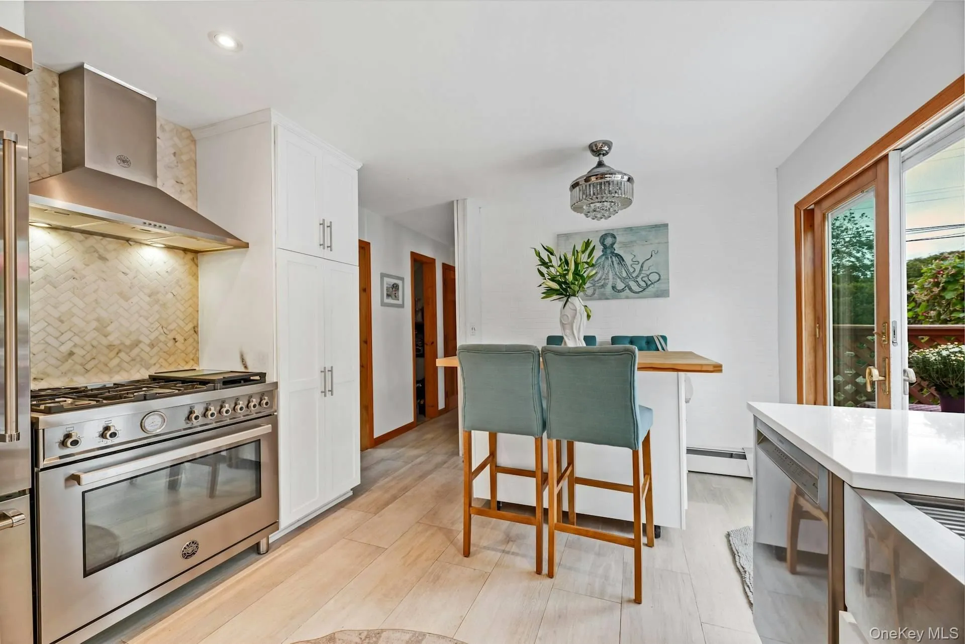 Kitchen featuring stainless steel stove, tasteful backsplash, wall chimney exhaust hood, white cabinetry, and light wood finished floors Kitchen featuring stainless steel stove, tasteful backsplash, wall chimney exhaust hood, white cabinetry, and light wood finished floors