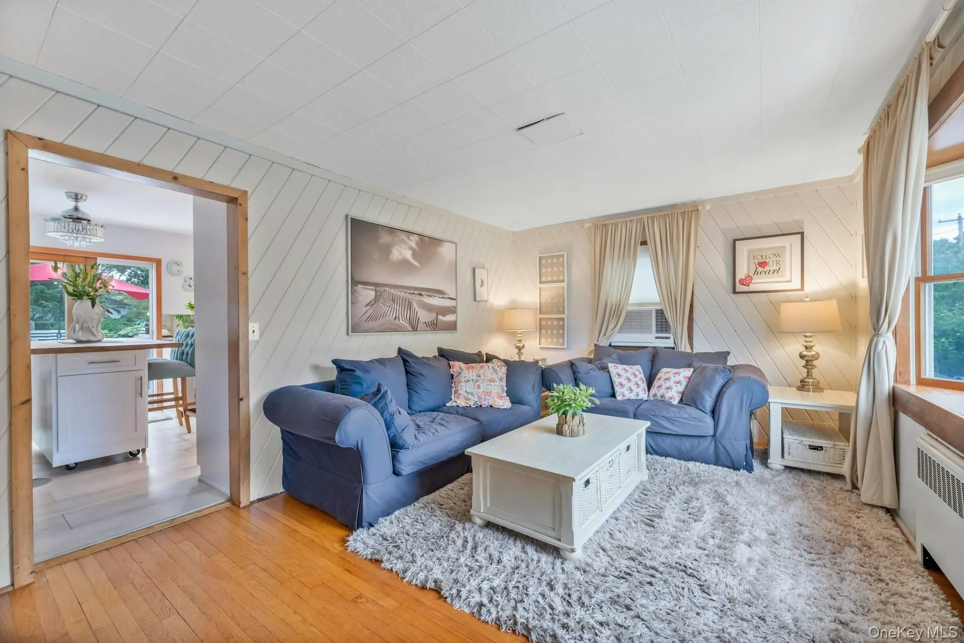 Living room featuring healthy amount of natural light, hardwood / wood-style floors, radiator, and wood walls Living room featuring healthy amount of natural light, hardwood / wood-style floors, radiator, and wood walls