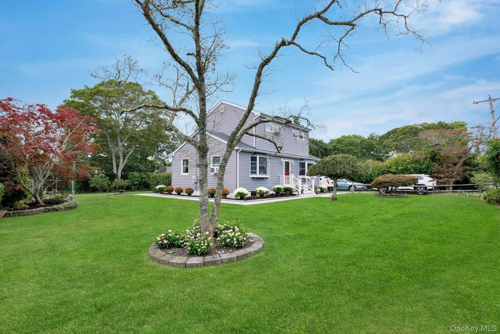 Colonial inspired home featuring a front yard and view of wooded area Colonial inspired home featuring a front yard and view of wooded area
