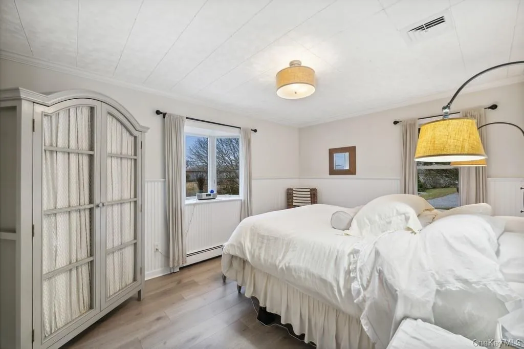 Bedroom featuring wood finished floors, crown molding, and a wainscoted wall Bedroom featuring wood finished floors, crown molding, and a wainscoted wall