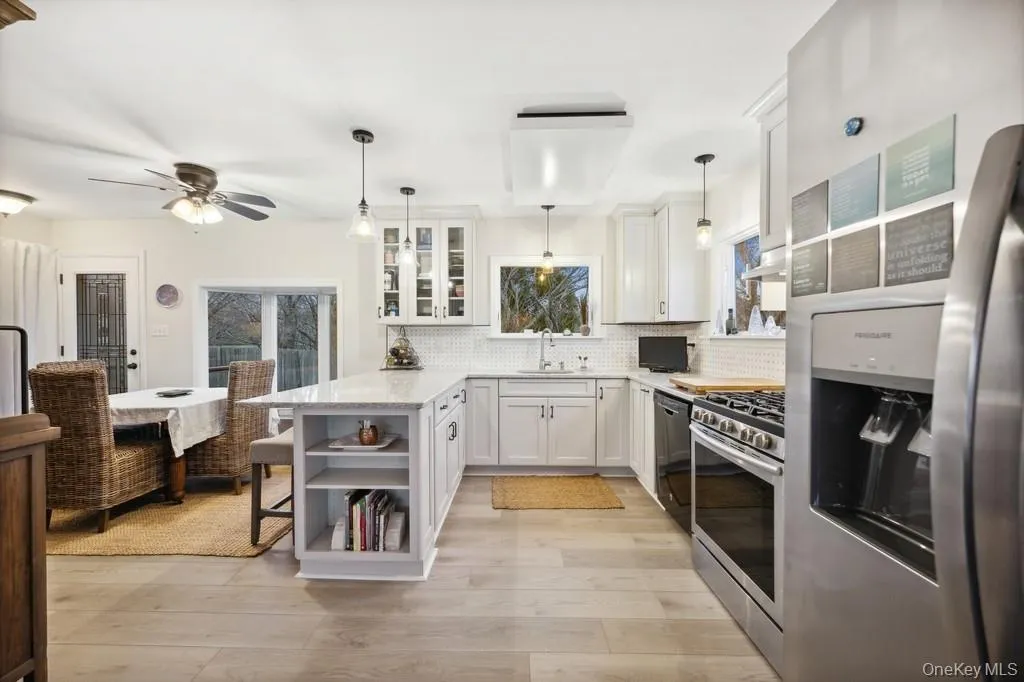 Kitchen with stainless steel appliances, a peninsula, a kitchen bar, open shelves, and glass insert cabinets Kitchen with stainless steel appliances, a peninsula, a kitchen bar, open shelves, and glass insert cabinets