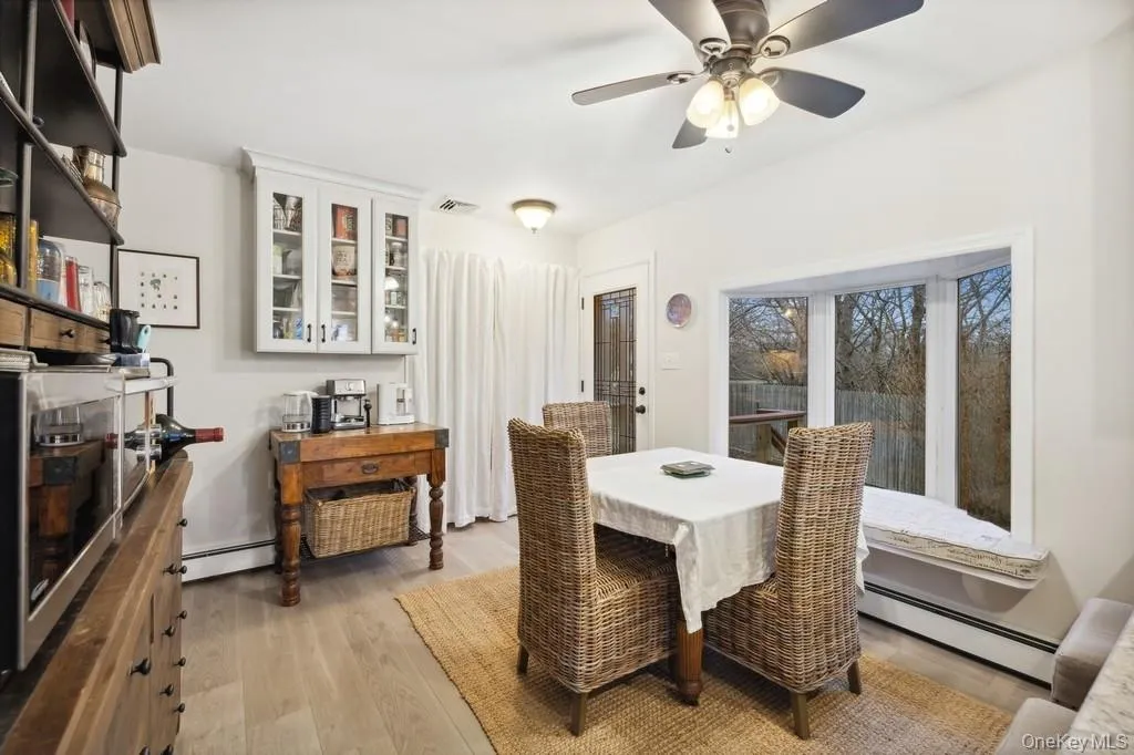 Dining area featuring a baseboard radiator, light wood-type flooring, and a ceiling fan Dining area featuring a baseboard radiator, light wood-type flooring, and a ceiling fan