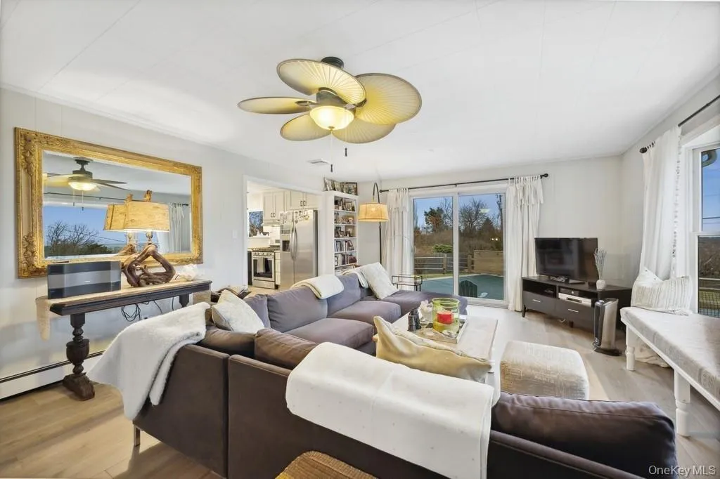 Living area with light wood-style floors, plenty of natural light, and ceiling fan Living area with light wood-style floors, plenty of natural light, and ceiling fan