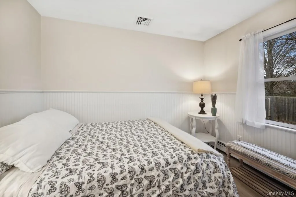 Bedroom featuring a wainscoted wall and a baseboard heating unit Bedroom featuring a wainscoted wall and a baseboard heating unit