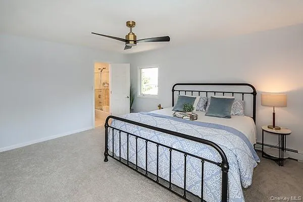 Carpeted bedroom featuring a ceiling fan and connected bathroom Carpeted bedroom featuring a ceiling fan and connected bathroom