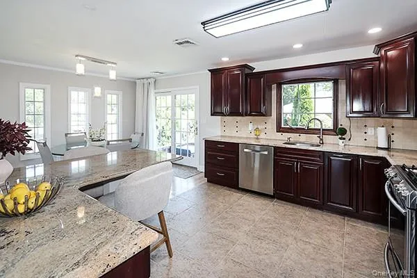 Kitchen featuring decorative backsplash, dark brown cabinets, appliances with stainless steel finishes, recessed lighting, and light stone countertops Kitchen featuring decorative backsplash, dark brown cabinets, appliances with stainless steel finishes, recessed lighting, and light stone countertops