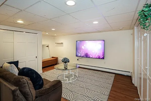 Living area with a paneled ceiling, wood finished floors, recessed lighting, and a baseboard radiator Living area with a paneled ceiling, wood finished floors, recessed lighting, and a baseboard radiator