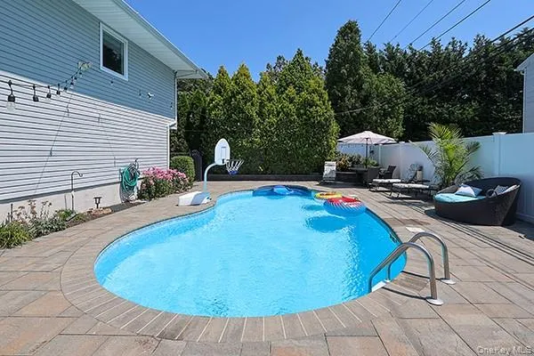 View of pool featuring a patio, a fenced backyard, and view of scattered trees View of pool featuring a patio, a fenced backyard, and view of scattered trees