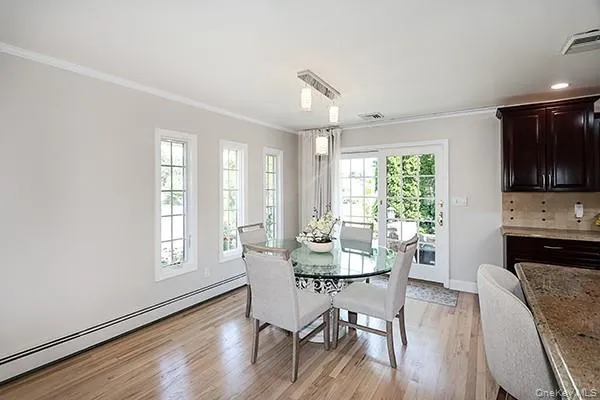 Dining room with a baseboard heating unit, ornamental molding, and light wood-style floors Dining room with a baseboard heating unit, ornamental molding, and light wood-style floors