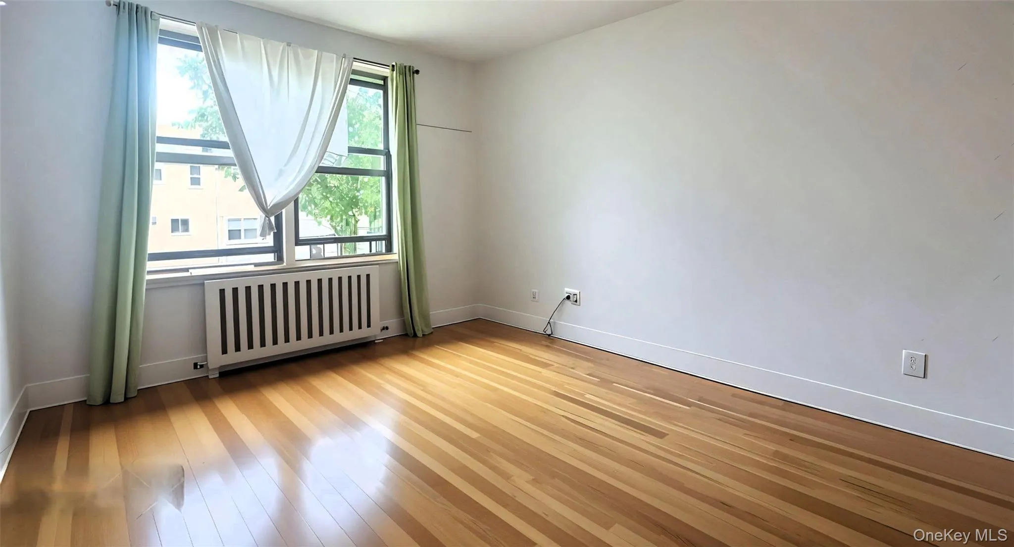 Spare room featuring radiator heating unit and light wood finished floors Spare room featuring radiator heating unit and light wood finished floors