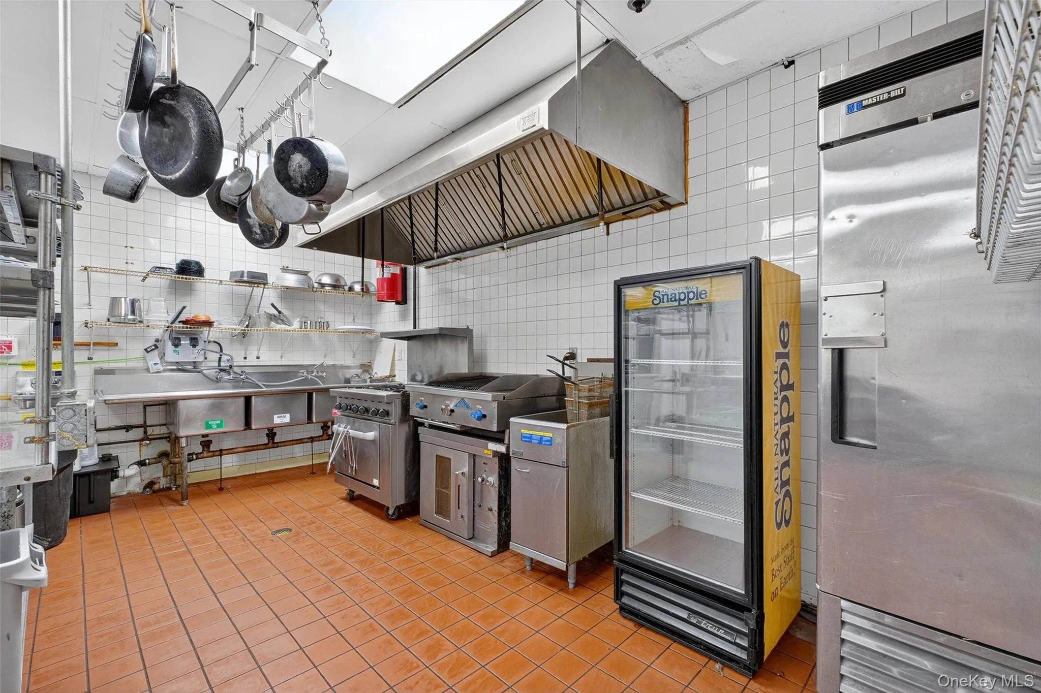 Kitchen featuring freestanding refrigerator, ventilation hood, and open shelves Kitchen featuring freestanding refrigerator, ventilation hood, and open shelves
