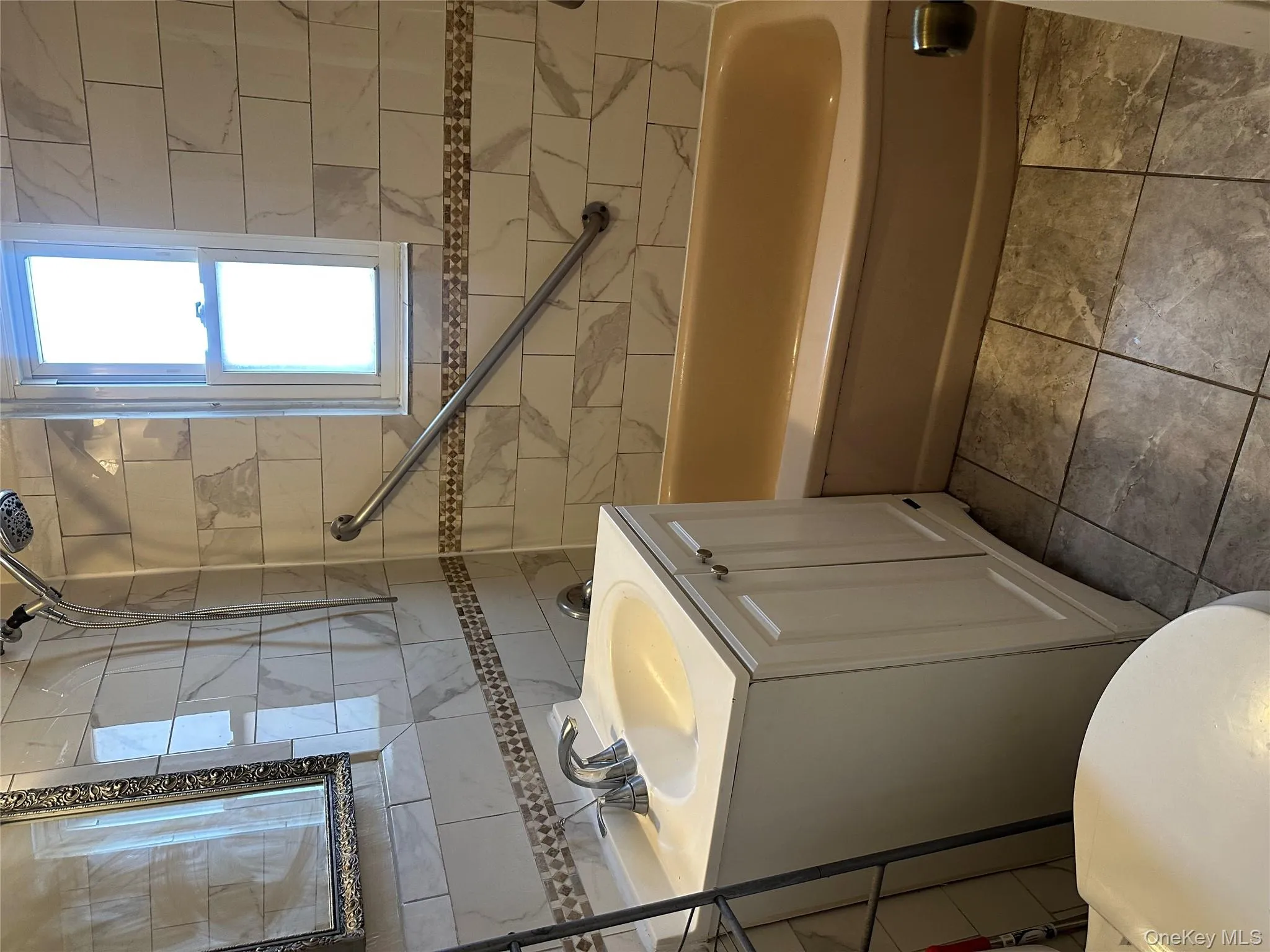 Full bathroom with vanity, tile walls, shower / bathtub combination, tasteful backsplash, and light tile patterned flooring Full bathroom with vanity, tile walls, shower / bathtub combination, tasteful backsplash, and light tile patterned flooring