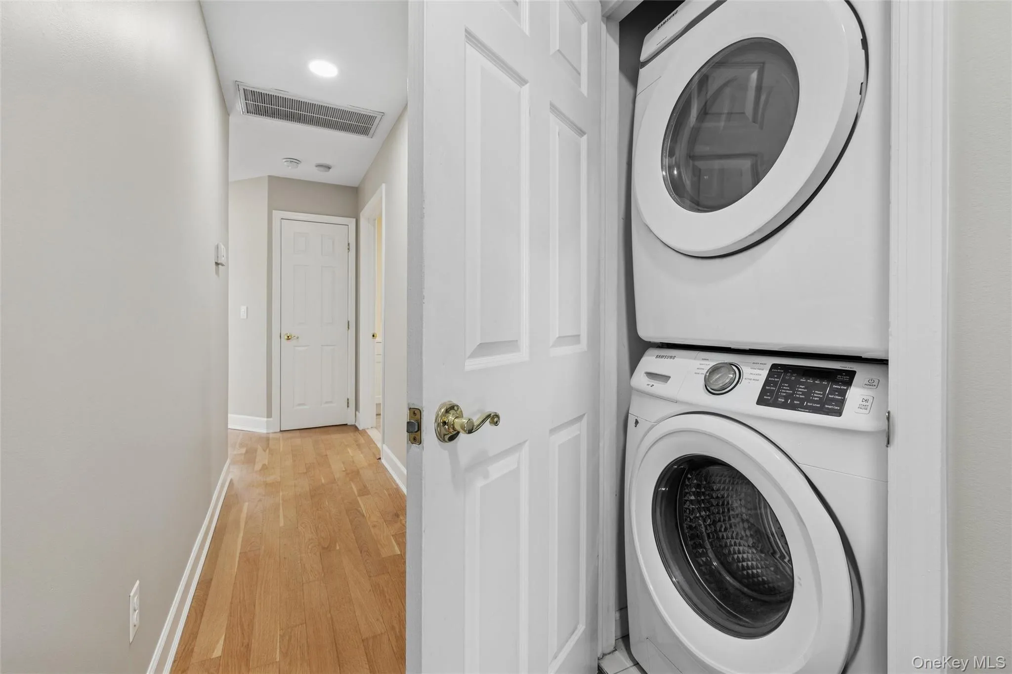Washroom with stacked washer / drying machine, hardwood / wood-style flooring, and recessed lighting Washroom with stacked washer / drying machine, hardwood / wood-style flooring, and recessed lighting