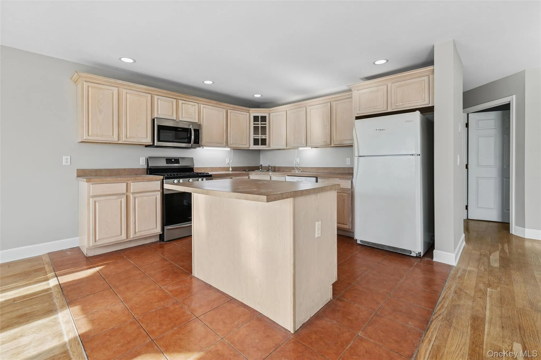 Kitchen with stainless steel appliances, light brown cabinetry, light tile patterned floors, and recessed lighting Kitchen with stainless steel appliances, light brown cabinetry, light tile patterned floors, and recessed lighting