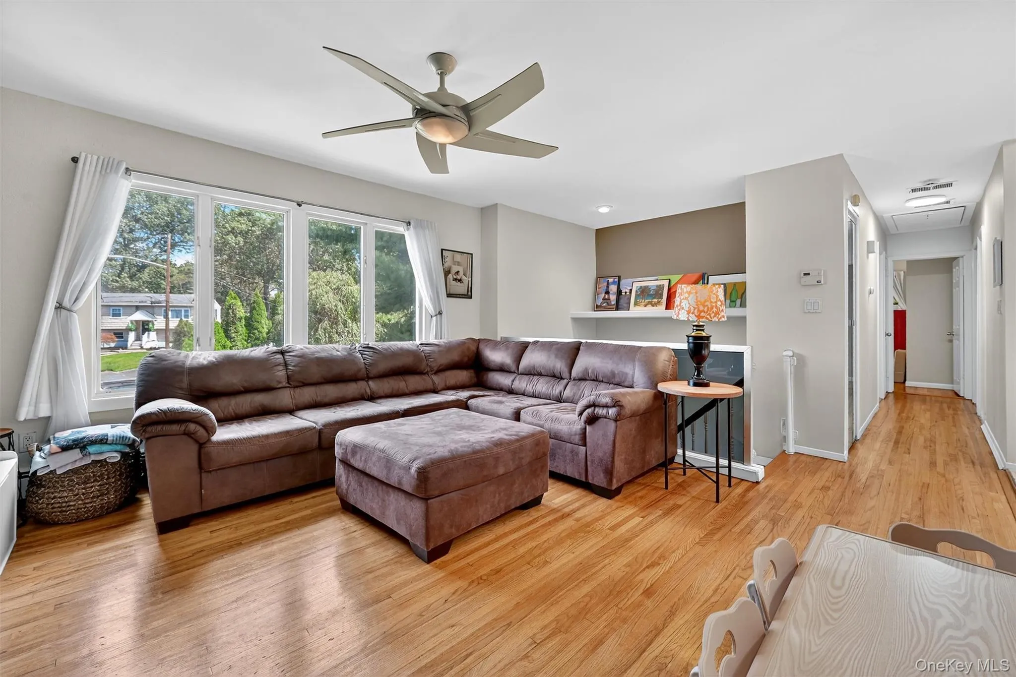Living room featuring light wood finished floors and a ceiling fan Living room featuring light wood finished floors and a ceiling fan