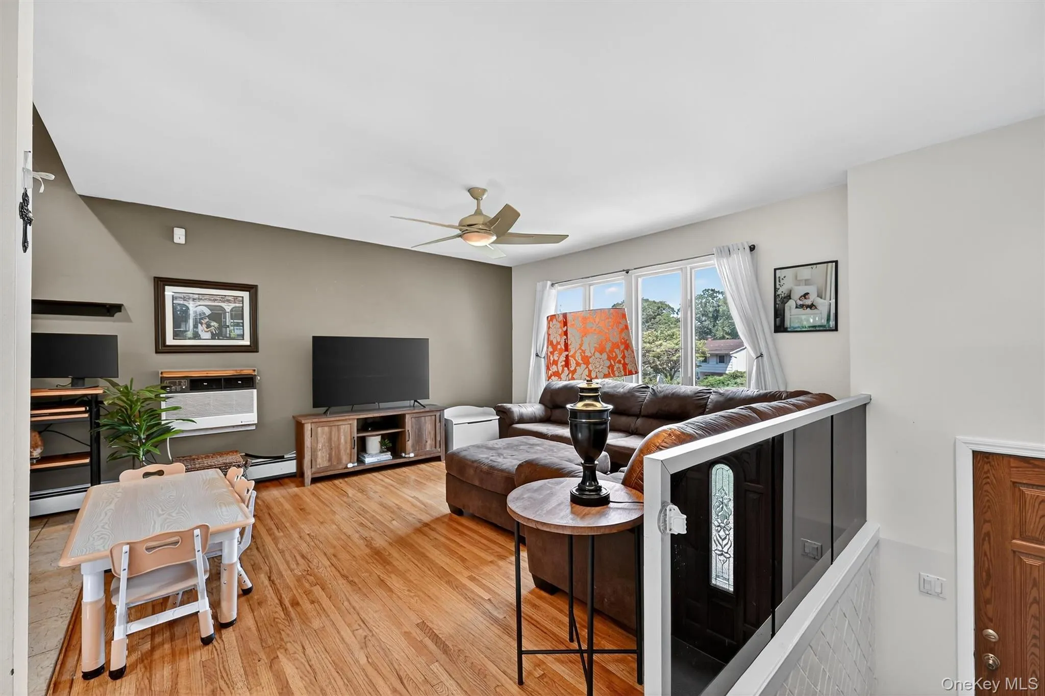 Living area featuring light wood-style flooring, a ceiling fan, and baseboard heating Living area featuring light wood-style flooring, a ceiling fan, and baseboard heating