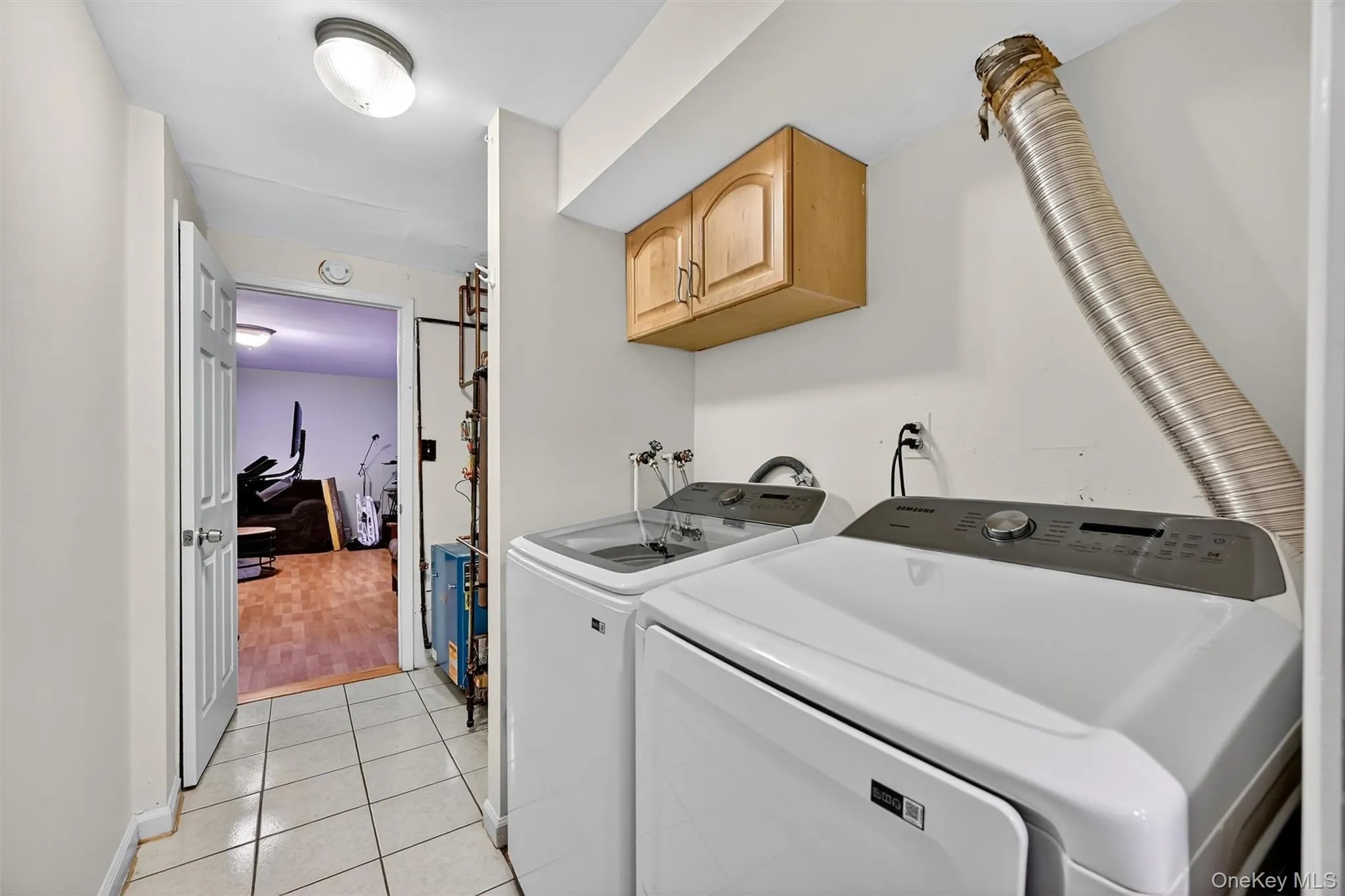 Laundry room with light tile patterned flooring, washing machine and clothes dryer, and cabinet space Laundry room with light tile patterned flooring, washing machine and clothes dryer, and cabinet space