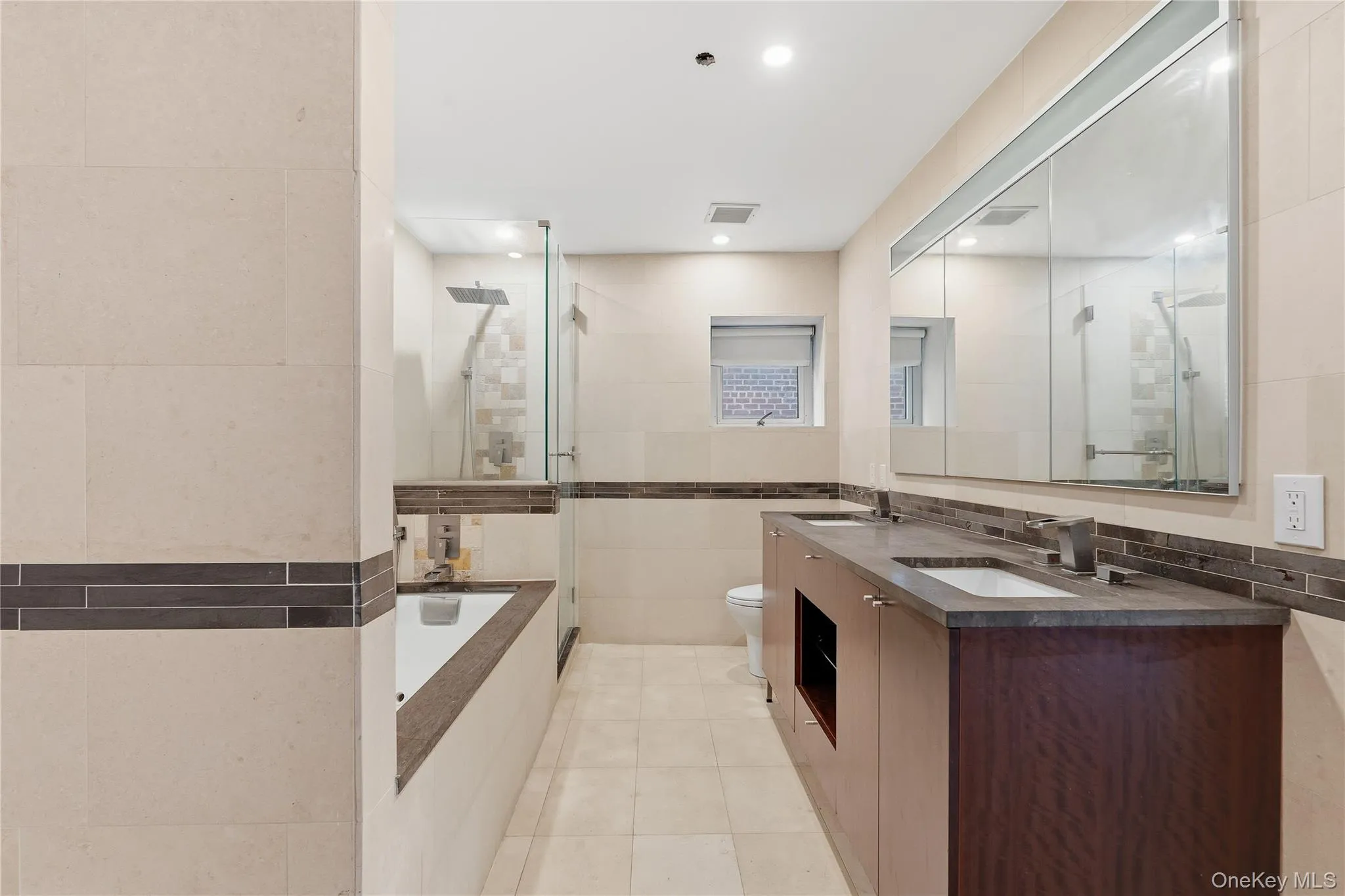 Bathroom with tile walls, double vanity, light tile patterned flooring, a stall shower, and a garden tub Bathroom with tile walls, double vanity, light tile patterned flooring, a stall shower, and a garden tub