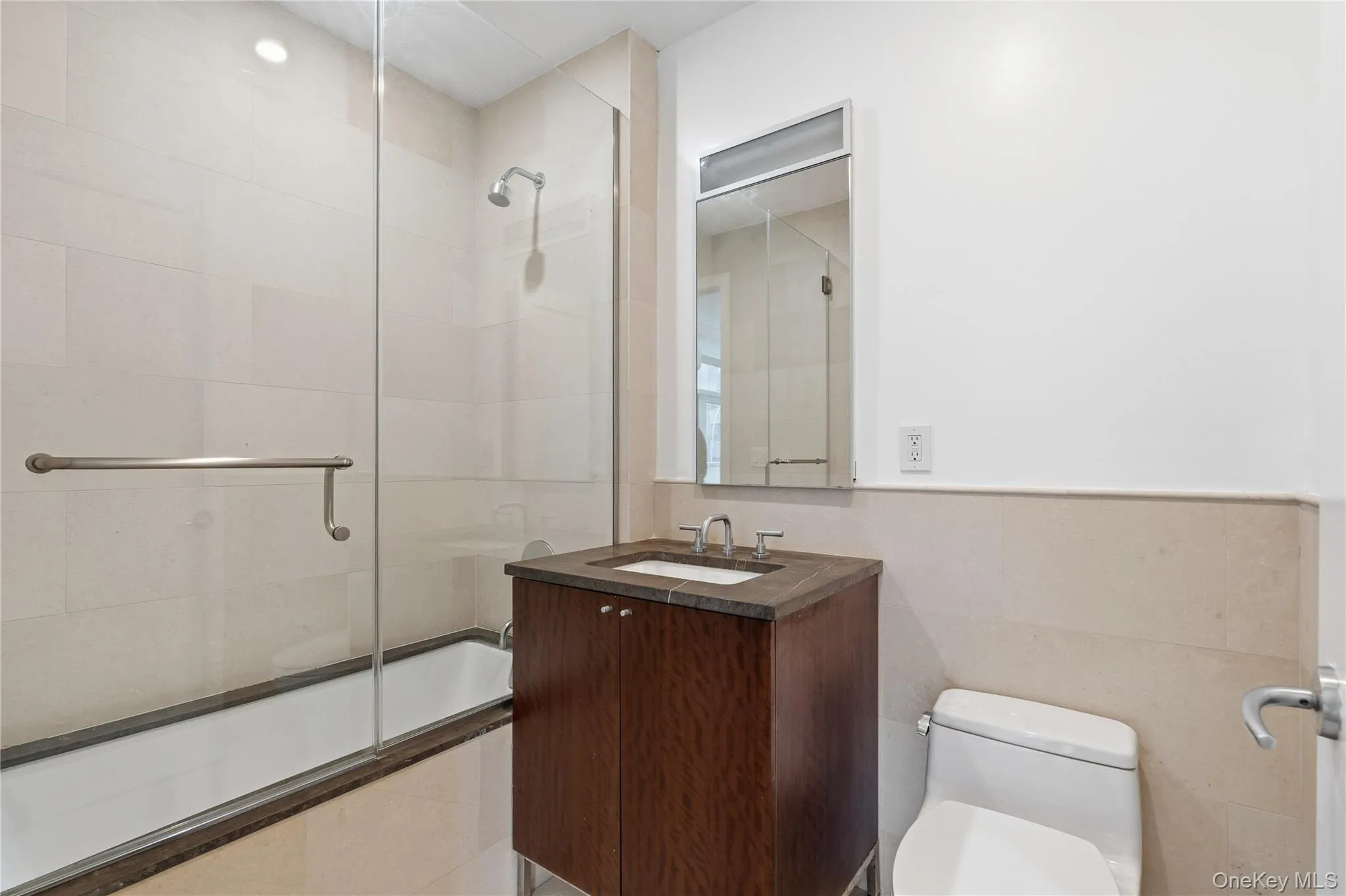 Bathroom featuring vanity, tiled shower / bath, and tile walls Bathroom featuring vanity, tiled shower / bath, and tile walls