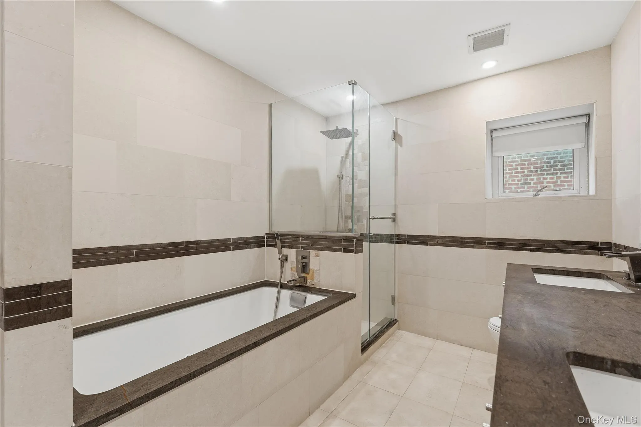Bathroom with double vanity, tile walls, a bath, light tile patterned flooring, and a shower stall Bathroom with double vanity, tile walls, a bath, light tile patterned flooring, and a shower stall