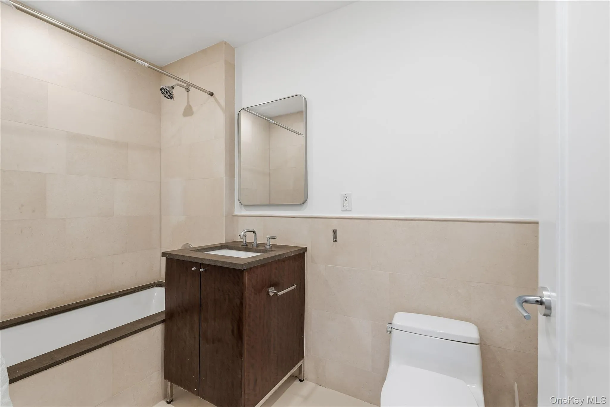 Full bath featuring tile walls, tiled shower / bath combo, vanity, and a wainscoted wall Full bath featuring tile walls, tiled shower / bath combo, vanity, and a wainscoted wall