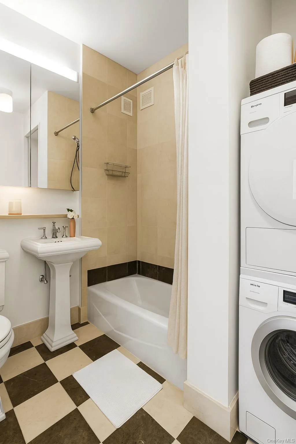 Bathroom featuring shower / bath combo with shower curtain and stacked washer and clothes dryer Bathroom featuring shower / bath combo with shower curtain and stacked washer and clothes dryer