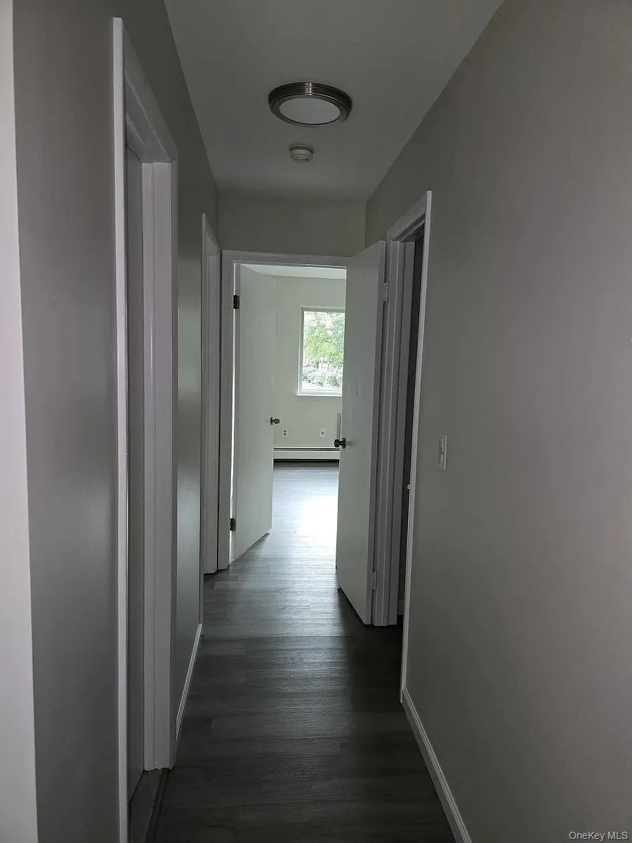 Hallway featuring dark wood-type flooring and a baseboard radiator Hallway featuring dark wood-type flooring and a baseboard radiator